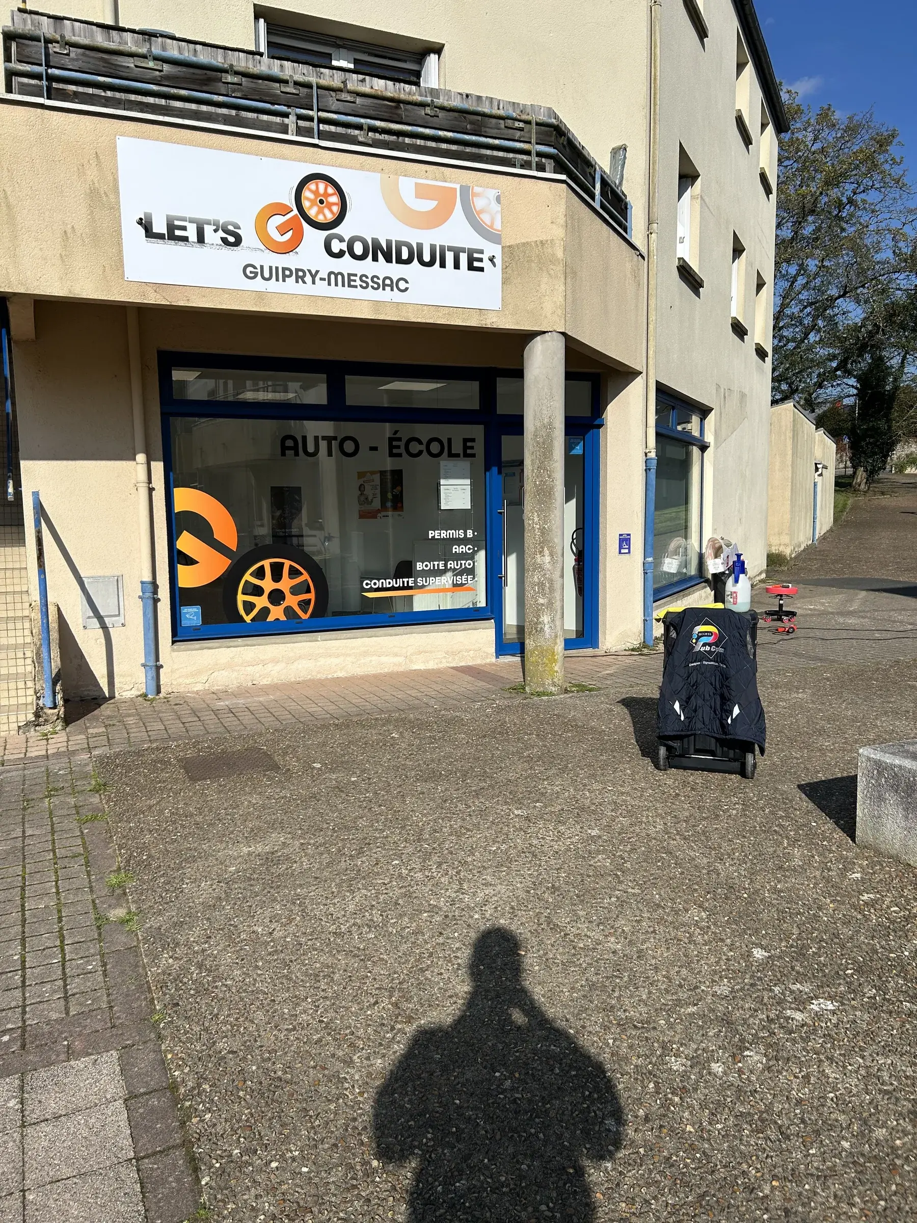 Panneau d'enseigne et lettrage adhésif blanc sur la vitrine d'une auto-école, au rez-de-chaussée d'un immeuble