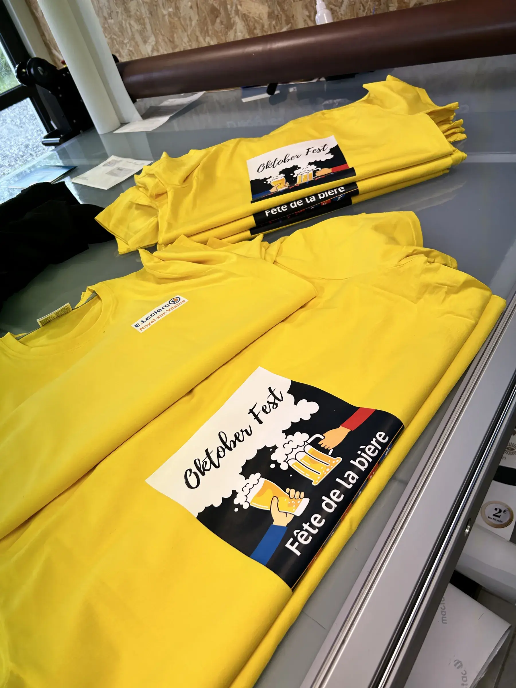 Tee-shirts jaunes imprimés d'un visuel de fête de la bière, pliés sur un plan de travail