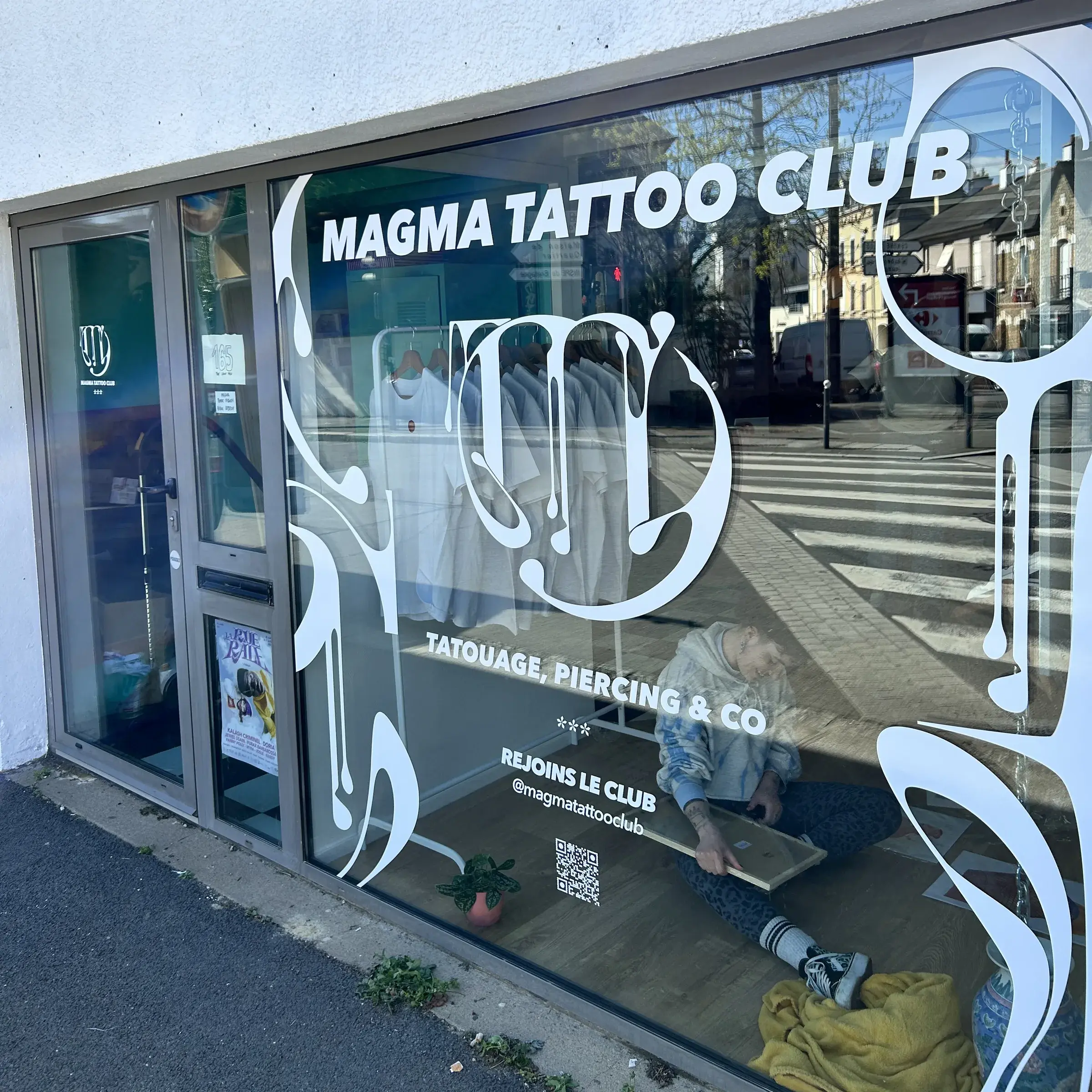Vitrine d'un salon de tatouage habillée de lettrage et de motifs adhésifs blancs
